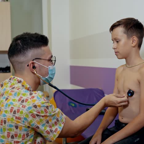 doctor pediatrician listens to the heartbeat and breathing of a sick teenager. checking the lungs and bronchi with a phonendoscope