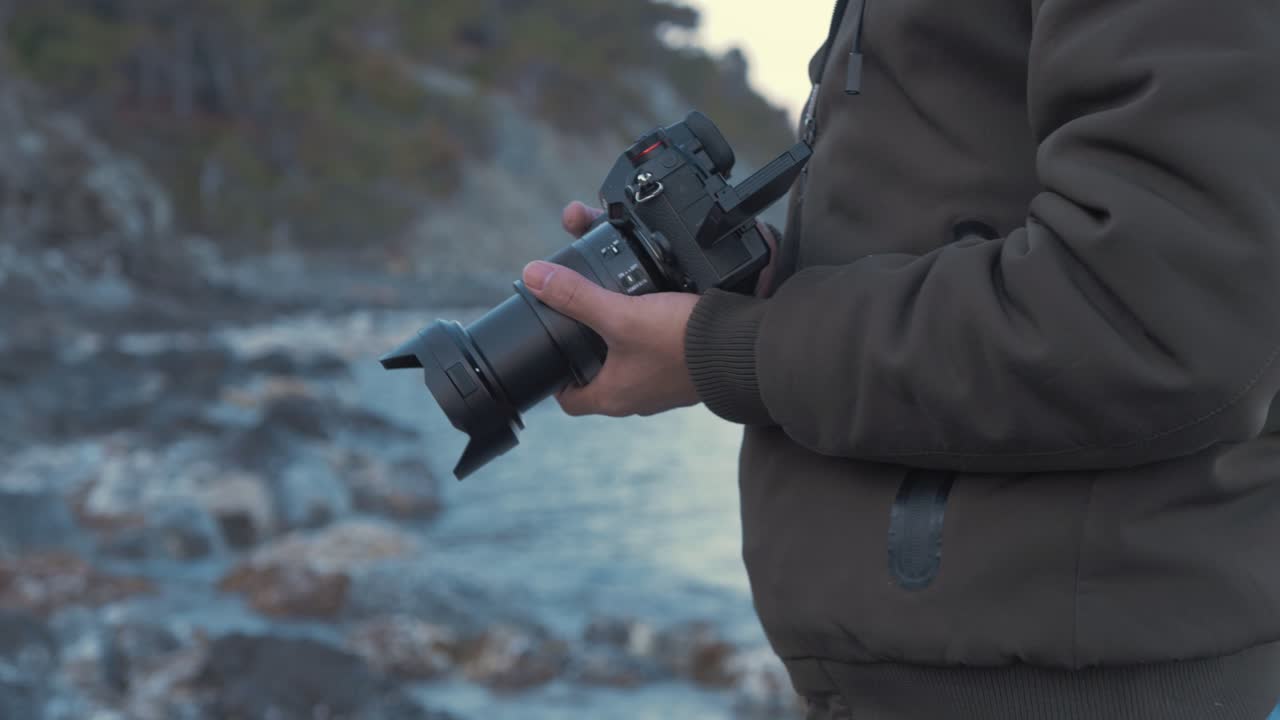 Giovane uomo riprende con la telecamera in riva al mare