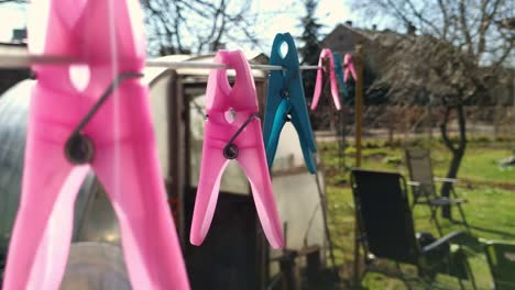 close up of colorful pink blue clothespins hanging outside sunny day garden, static, focus on foreground, day