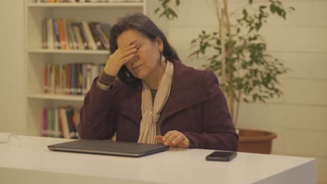 old secretary woman closing laptop after exhausted day at work,close up portrait