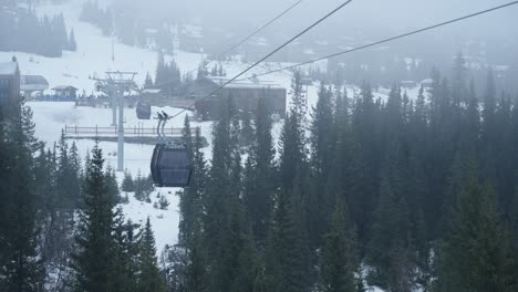 4K-cable-car-going-towards-the-camera-between-two-snowy-mountains-crossing-the-mountain-valley-on-a-misty-winter-day-in-Norway