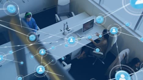 animation of network of digital icons against overhead view of diverse people working at office