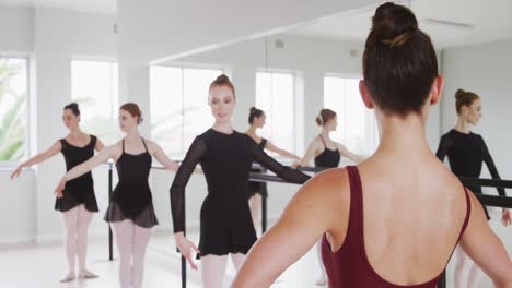 caucasian ballet female dancers exercising with a barre by a mirror during a ballet class