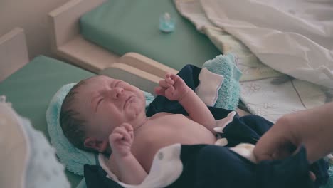 mother puts on crying baby holiday suit on changing table