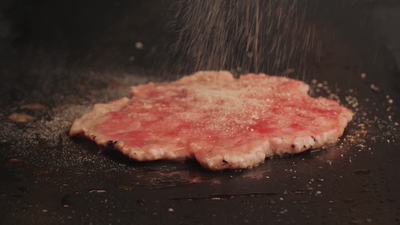 Cooking American fat smash burger on grill close-up. Beef or pork cutlet smashing by burger press. The chef in kitchen of the restaurant making cutlets for burgers - smash burger beefsteak. Fast and street food concept. High quality 4k footage