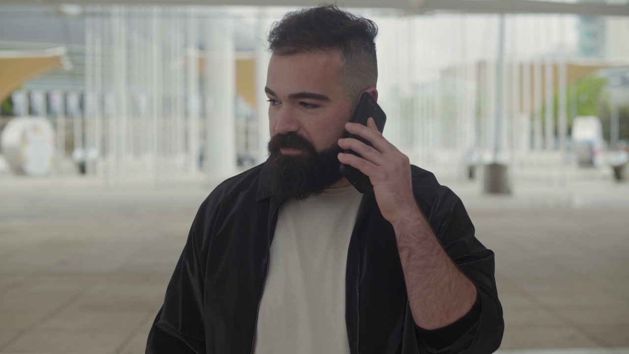 집중된 젊은이가 밖에서 전화로 이야기하고 있습니다.