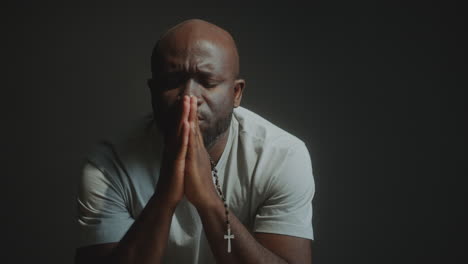 faithful man holding cross and praying deeply to god