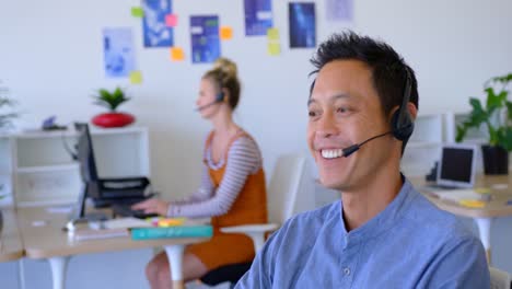 Young-Asian-male-executive-talking-on-headset-at-desk-4k