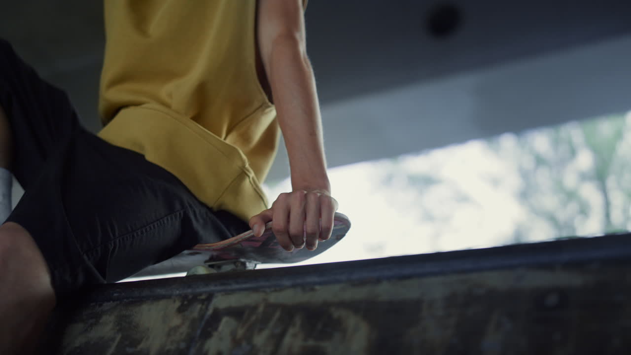 인식할 수 없는 스케이트 선수가 스케이트 파크에서 휴식을 취하고 있습니다. 익명의 남자가 훈련 후 휴식을 취하고 있습니다.