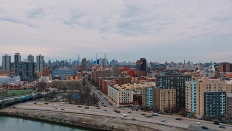 Rising-shot-reveal-of-Manhattan-New-York-City-from-Harlem,-4K-drone,-day