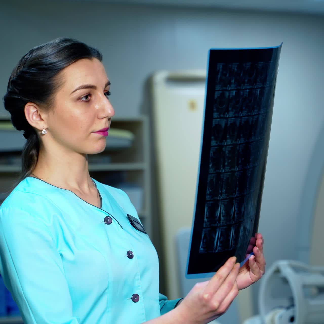 Woman doctor is watching x-ray in clinic. Young female expert holding x-ray photo in hands in modern hospital. Medical concept.