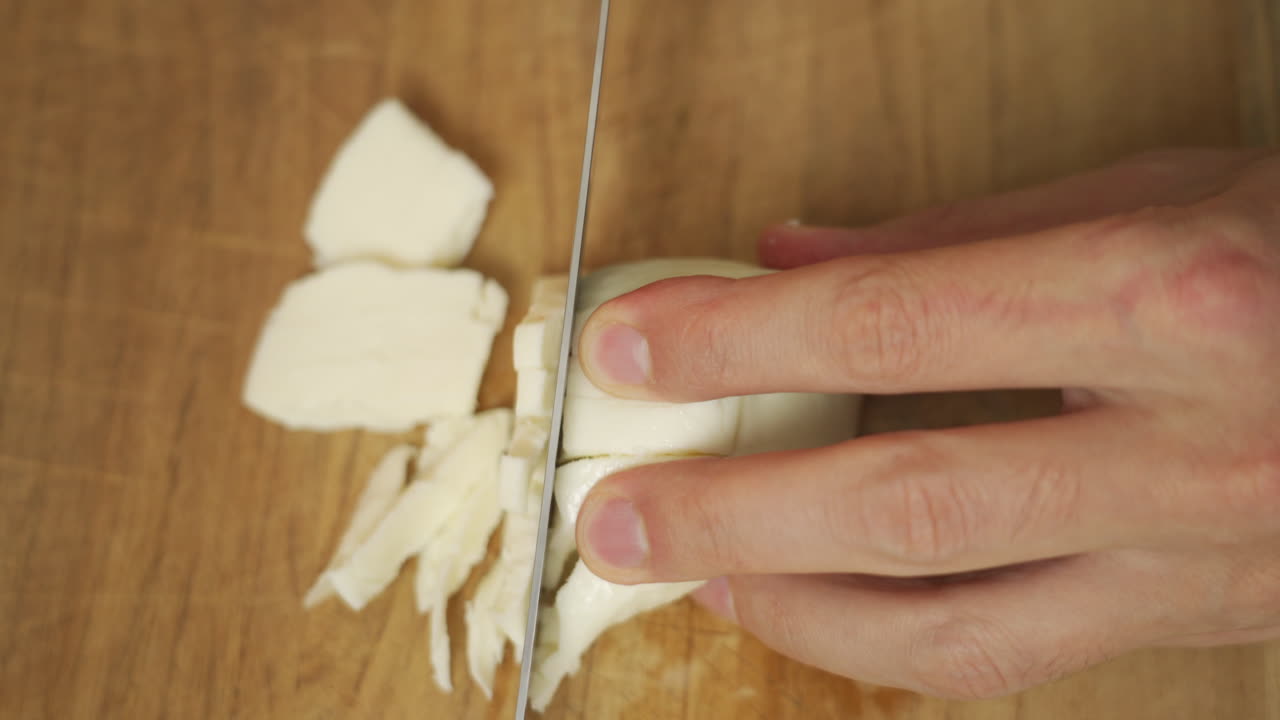 Top view of a chef slicing mozzarella