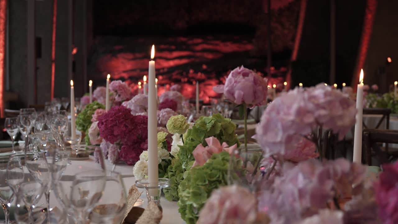 Tavolo elegantemente apparecchiato con ortensie rosa e lume di candela in una romantica scena di evento serale.