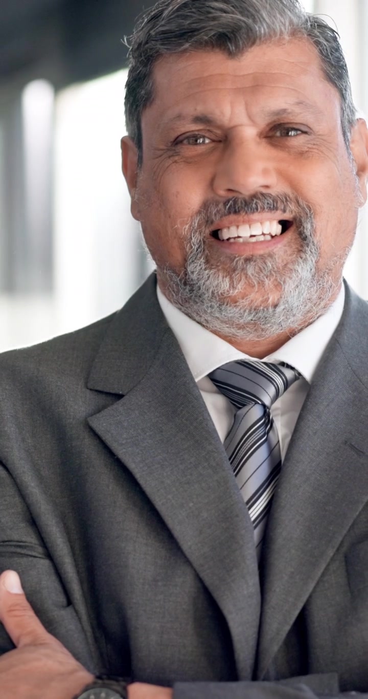 Confident Mature Businessman Smiling and Crossing Arms in Office