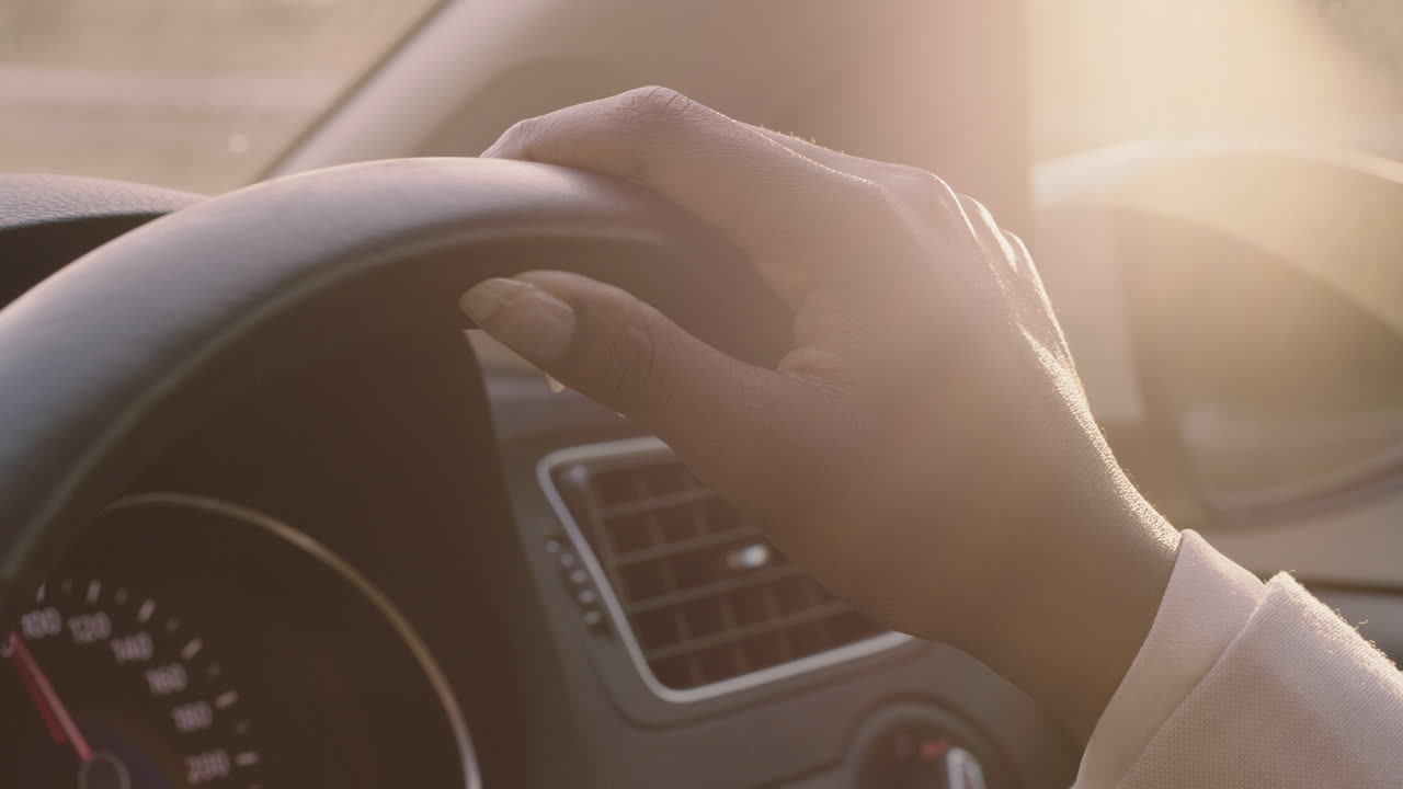 donna che guida un'auto con le mani sul volante per controllare il veicolo in città che viaggia sulla strada all'ora di punta verso la destinazione