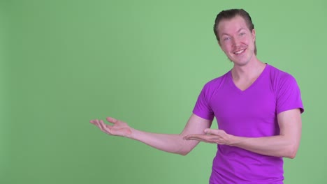 fotografía de estudio de un joven sonriendo y mostrando el espacio de copia contra un fondo verde
