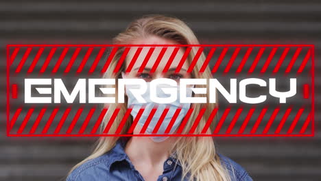 animation of text emergency, over woman wearing face mask in city street