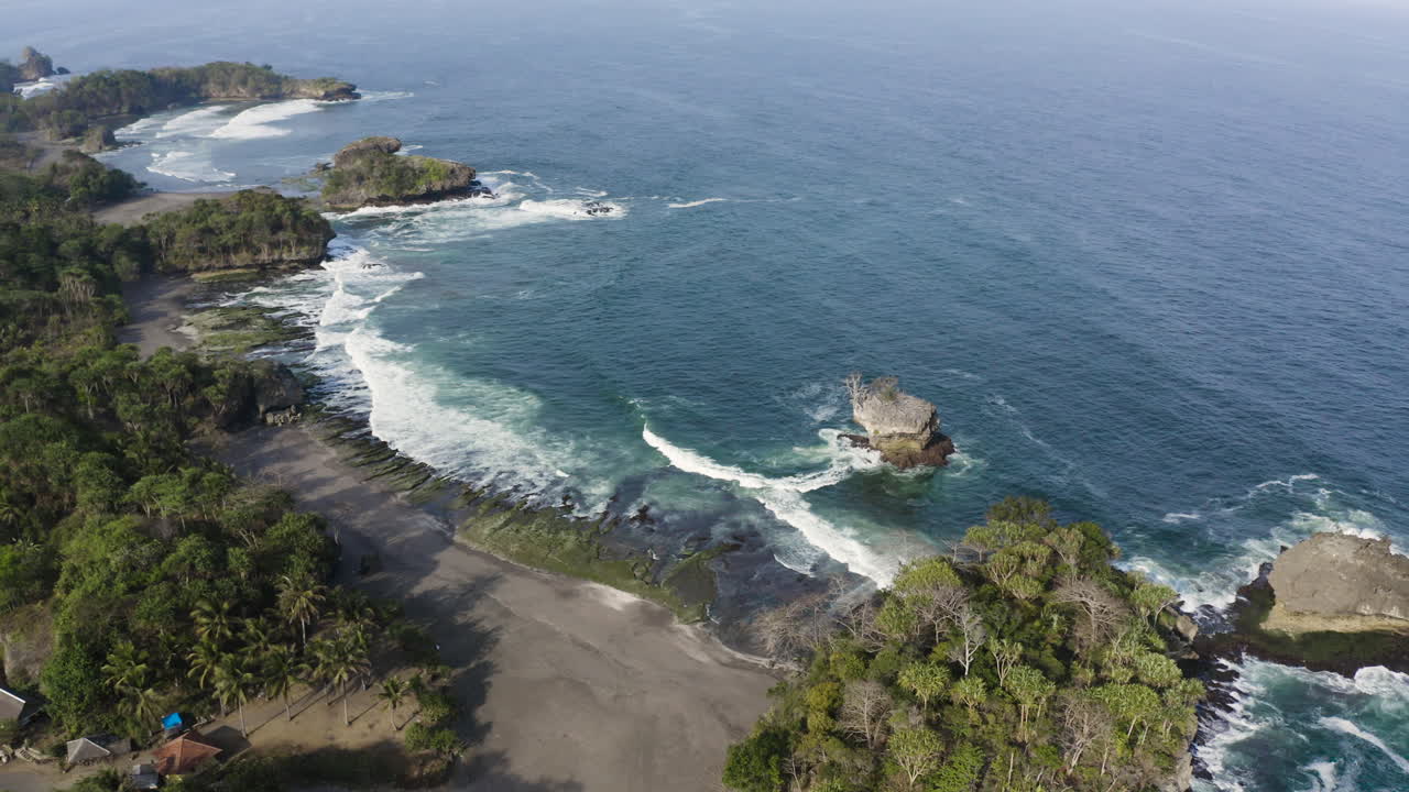 Aerial view of a tropical beach with waves and rocky formations