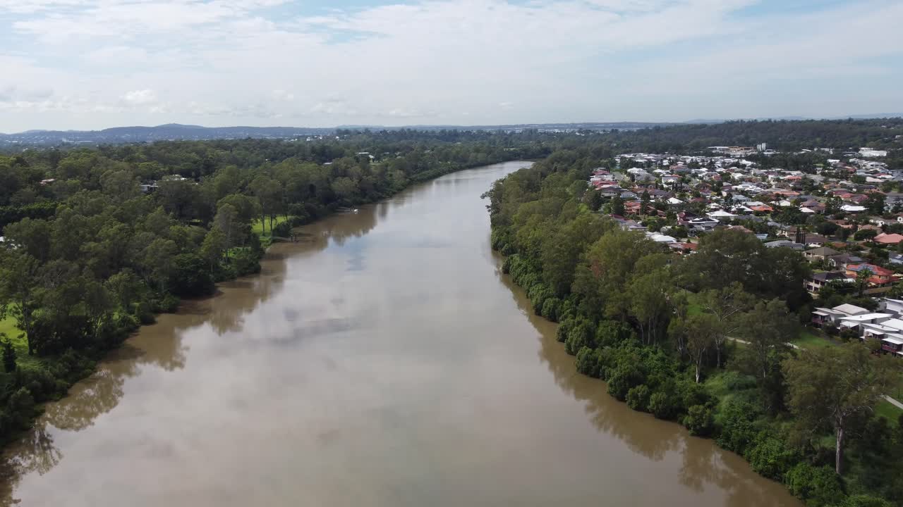 volando sobre un río marrón y casas visibles a la derecha