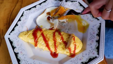 person eating fried egg and omelette