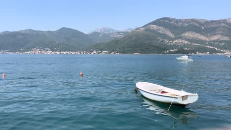 Standbildvideo-Von-Kleinen-Fischerbooten,-Die-Im-Wasser-Schaukeln-Und-Die-Hohen-Und-Felsigen-Berge-Auf-Der-Berühmten-Insel-Montenegro-Namens-Seveti-Stephan-überblicken