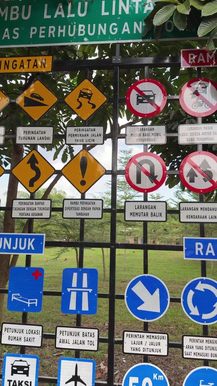 Collezione di segnali stradali indonesiani esposti su una griglia metallica