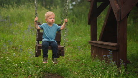 little sad boy plays swings spending time on playground