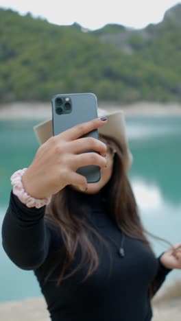 woman taking selfies by a scenic lake