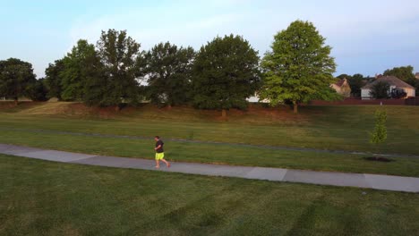 Steady-drone-footage-of-man-running-through-park