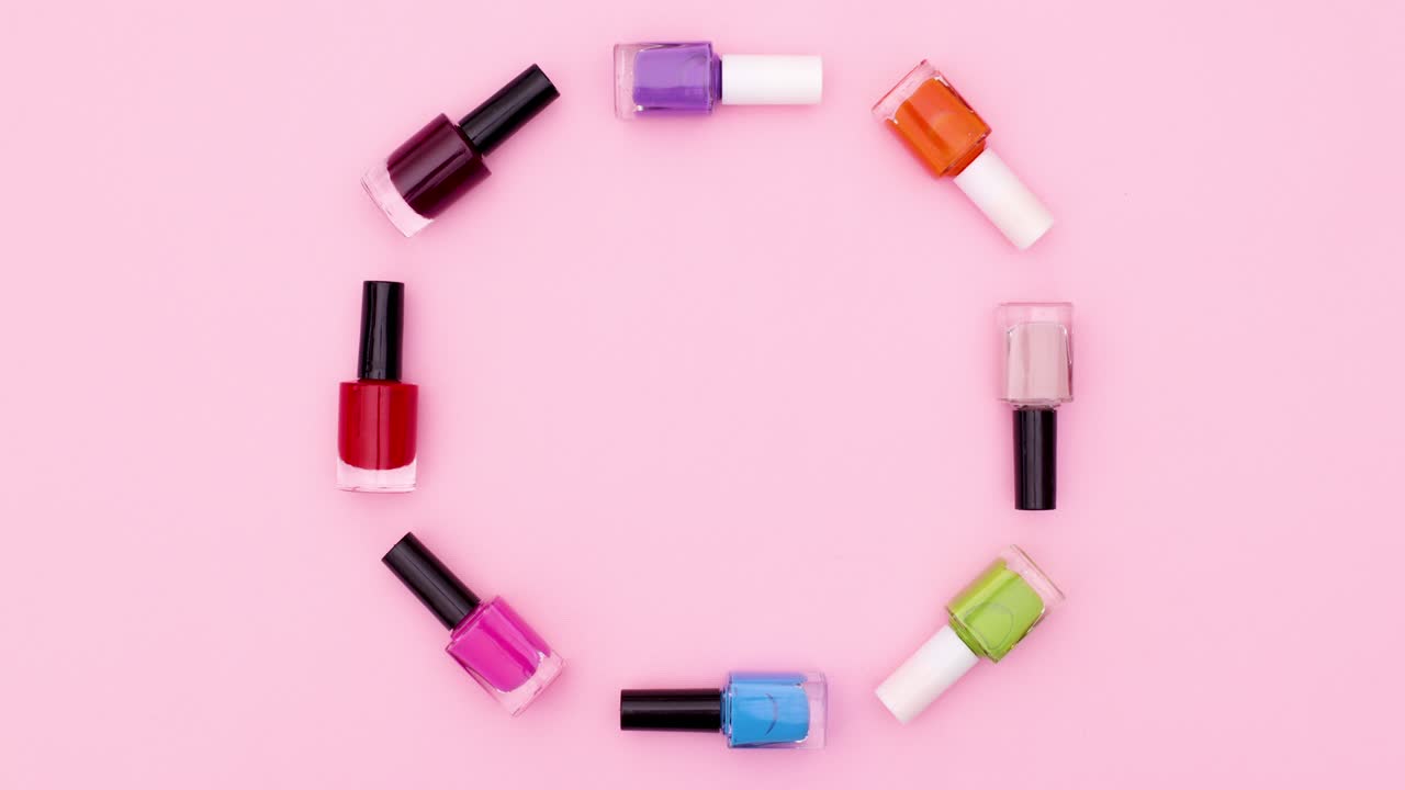 botellas coloridas de esmalte de uñas se mueven en círculo en el tema rosa. detener el movimiento