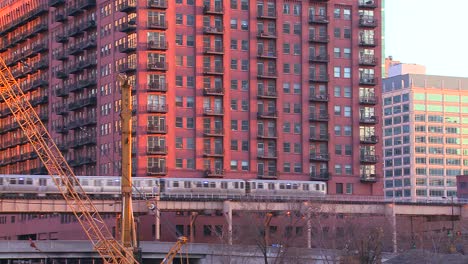 the el train travels over a bridge in front of the chicago skyline and apartments