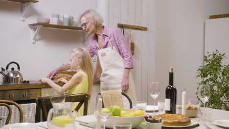 Little-Girl-Helping-Her-Grandmother-To-Set-Table-For-Dinner-And-Bringing-Plates