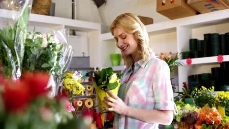 beautiful female florist smelling flower in flower shop