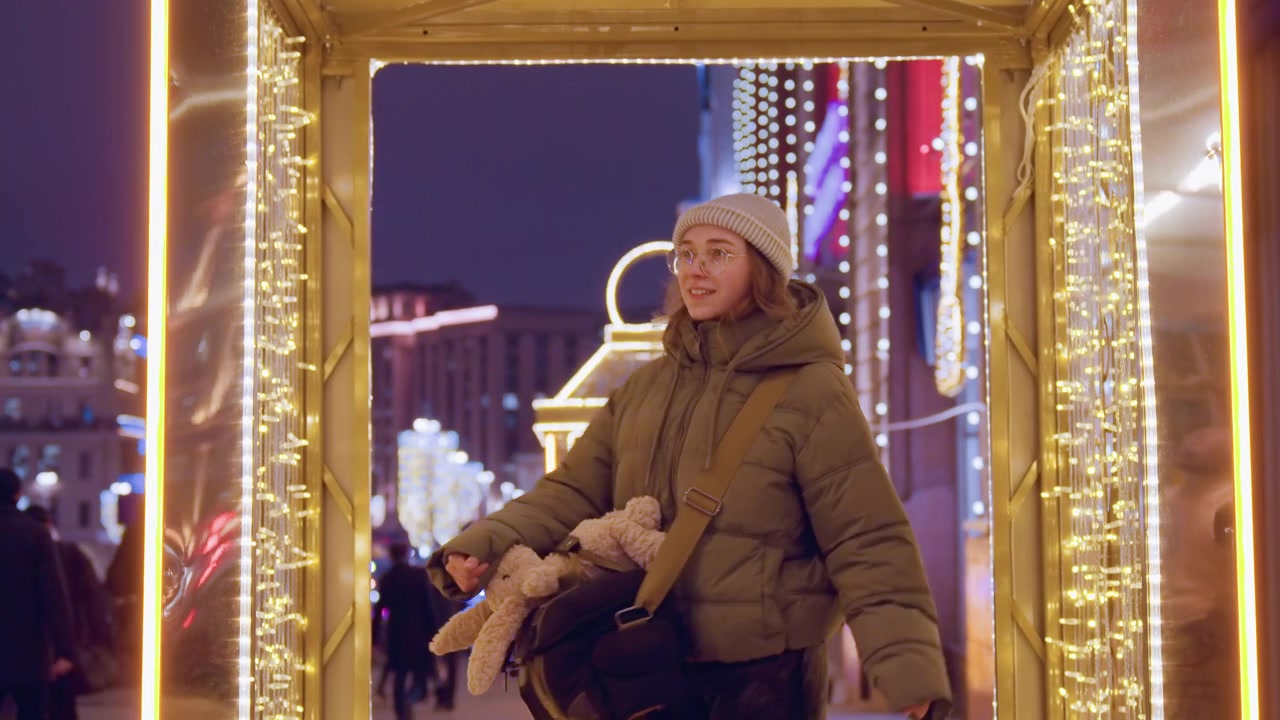 Mercato notturno della città. Donna sotto un arco illuminato. Silhouette di donna tra le luci festive del mercato di notte. Passeggiata cittadina illuminata con allegre bancarelle del mercato e donna che passa