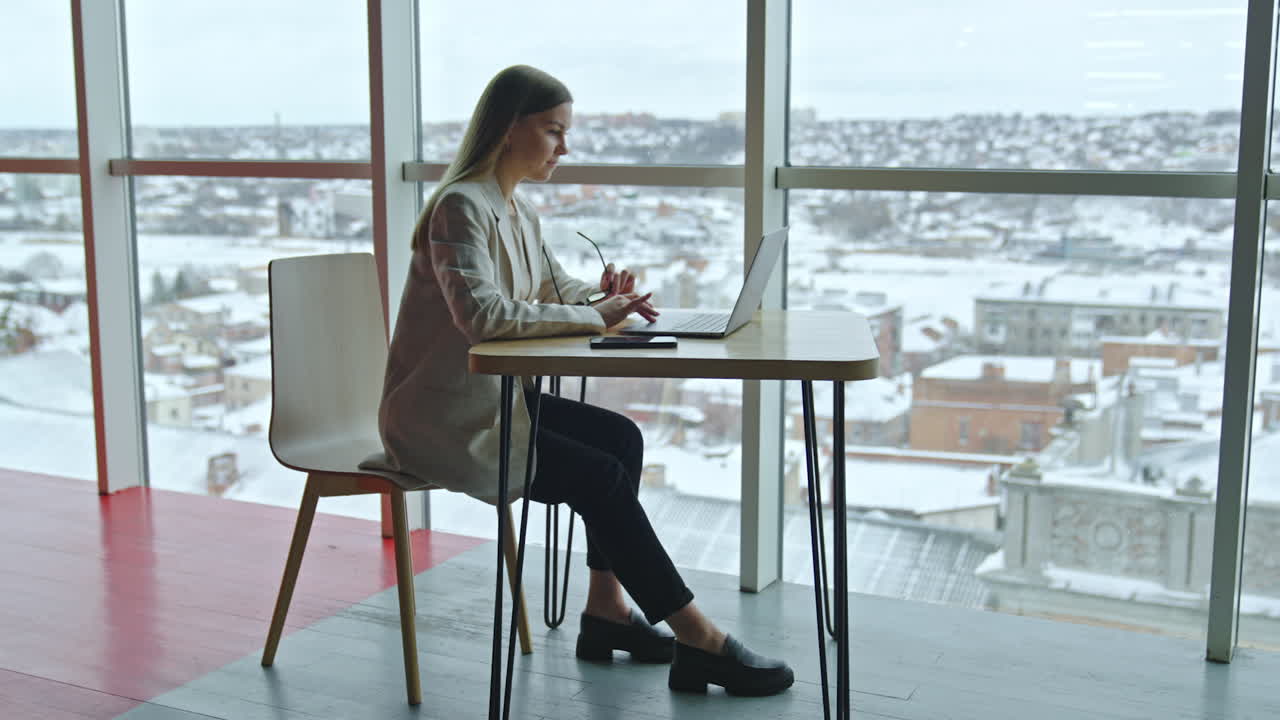 Businesswoman Working at a Window Desk in a Modern Office during Winter
