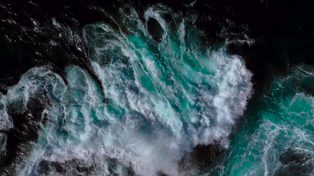 Stormy Waves Crashing Onto Foamy Surface Over Rocky Coastline. Aerial Slow Motion Shot