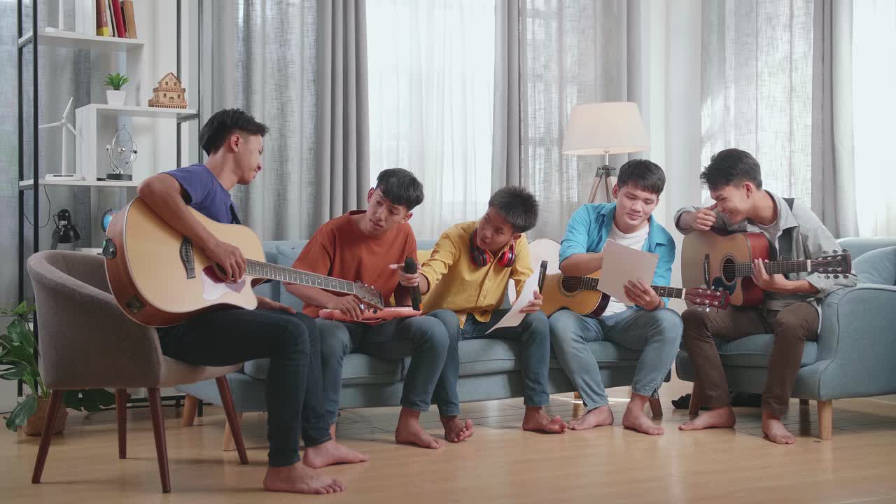 음악 악기를 가진 젊은 아시아 친구 그룹이 서로 도와서 집에서 종이에 음악을 작곡합니다.