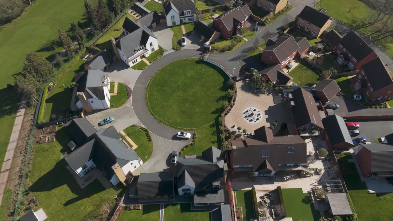 Aerial of circular eco-friendly neighborhood encircling communal green, flat-roof modern houses with solar arrays and driveways creating symmetrical community design
