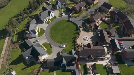 aerial of circular eco-friendly neighborhood encircling communal green, flat-roof modern houses with solar arrays and driveways creating symmetrical community design