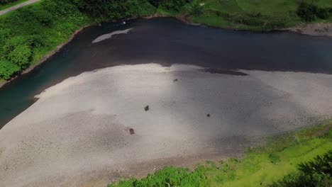 cloud shadows move by above sandy riverbank, terraced field, in green valley gorge