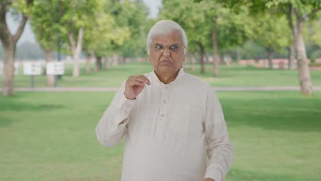 Disgusted-Indian-old-man-smelling-something-bad-in-park