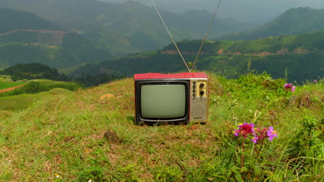Vídeo-Abstracto-De-Una-Vieja-Televisión-En-La-Cima-De-Una-Montaña-Verde,-Tecnología-De-Fusión-Natural