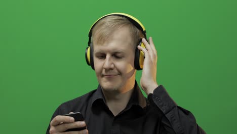 Guy-listens-to-music-in-wireless-yellow-headphones-and-dances.-Green-screen