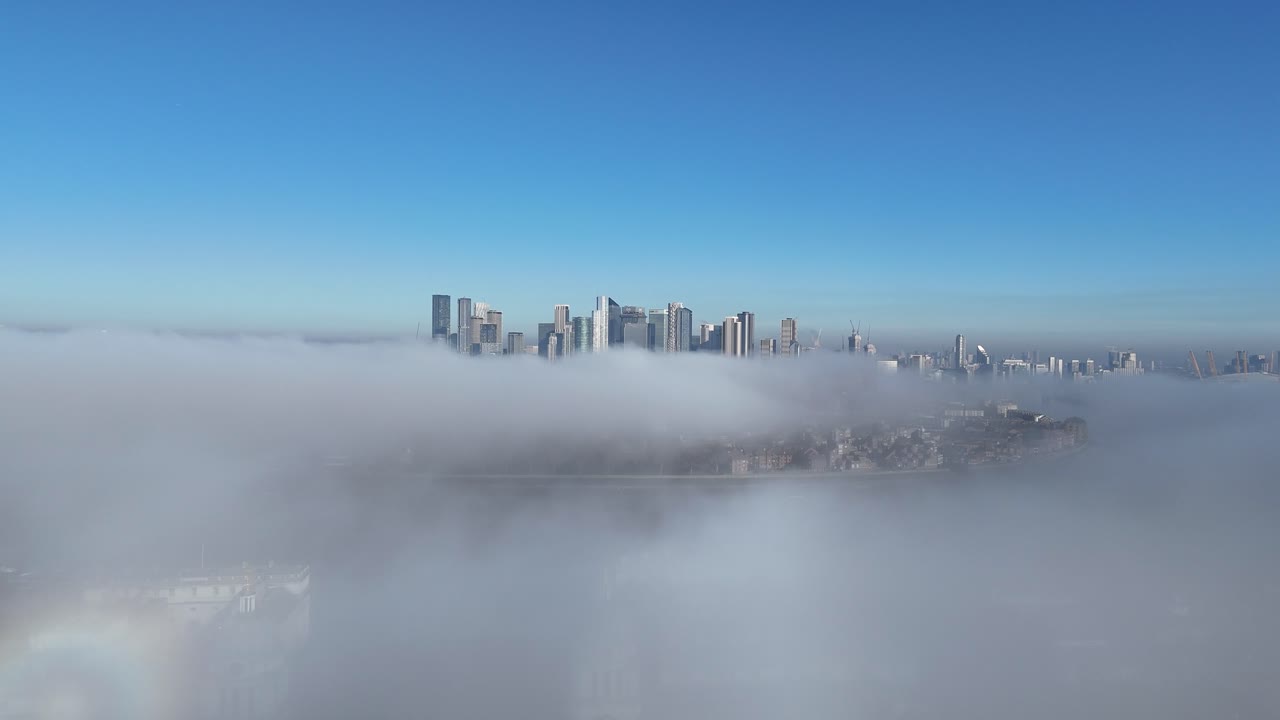 Breathtaking aerial view of Canary Wharf, London, as skyscrapers pierce through a mesmerizing cloud inversion, offering a dramatic, cinematic skyline experience.