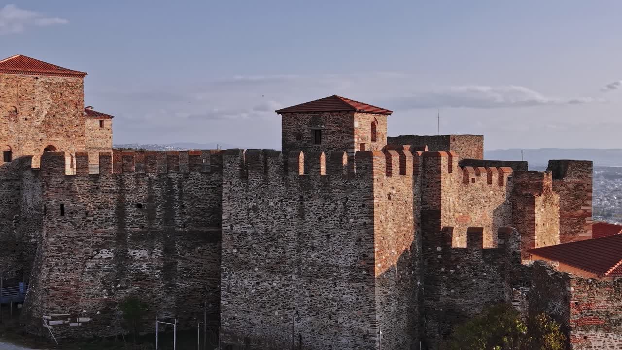 Vecchia fortezza si erge in Grecia sotto un cielo sereno con vista su una città in lontananza.