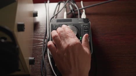 close-up shot of a hand operating a sound mixer, rotating its knob to adjust audio levels. the scene captures the precise control and technical skill required in sound engineering