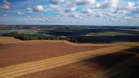 Aerial-wide-shot-of-golden-wheat-field-and-modern-photovoltaic-units-in-backdrop