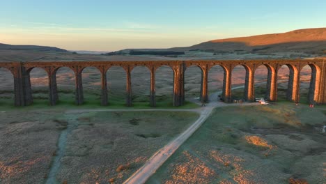 railway bridge with many arches catching dawn light spanning desolate moorland