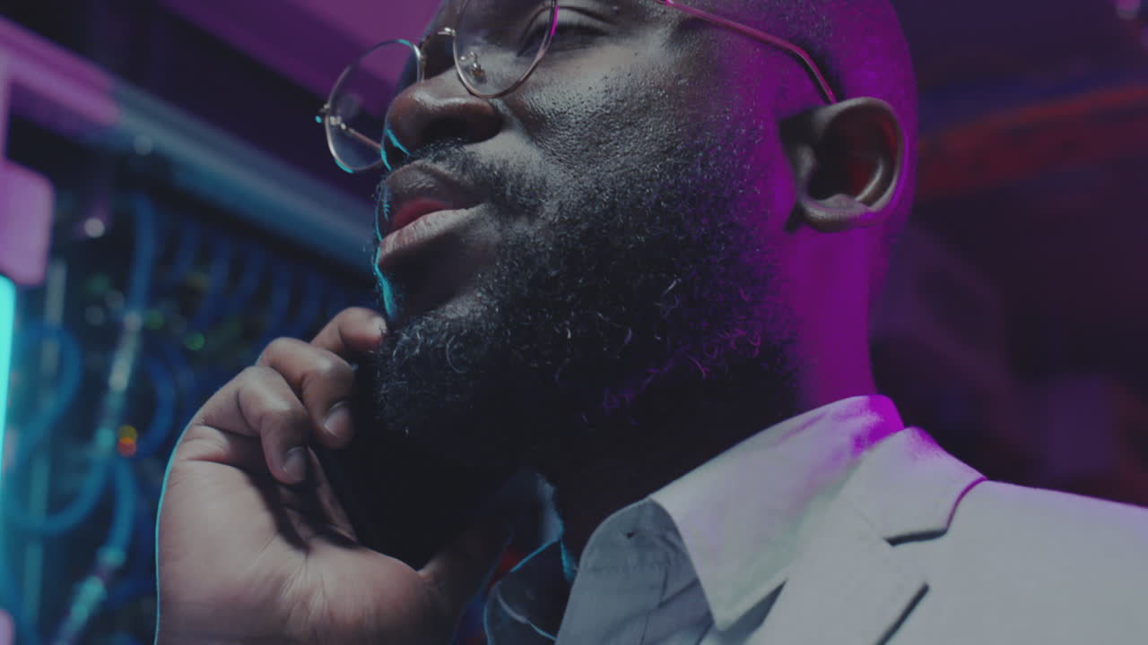 IT Professional Talking on Phone in a Neon-Lit Data Center