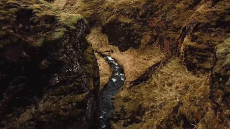 Vista-Aérea-De-Una-Corriente-De-Agua-Que-Fluye-En-Un-Desfiladero-De-Acantilados-En-Islandia,-Durante-El-Invierno